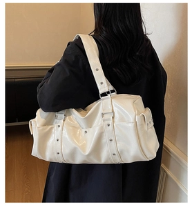 Detail of white glossy PU leather travel bag with silver studs and spacious pockets