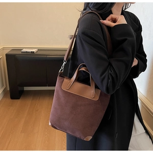 Detail of dark brown faux suede bucket bag showing leather handle and silver metal buckle