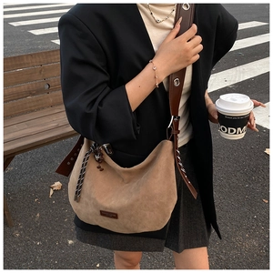 Détail du sac besace en daim kaki avec bandoulière marron et pendentif décoratif