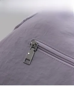 Detail of a smooth silver metal zipper on a durable purple nylon shoulder tote bag