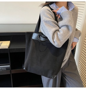Detail view of black canvas tote bag with leather reinforcement on model shoulder