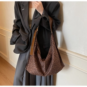 Détail du sac hobo léopard montrant la texture du tissu et la bandoulière en cuir à œillets