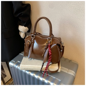 Détail du sac Boston en cuir ciré marron vintage avec pendentif tissé décoratif