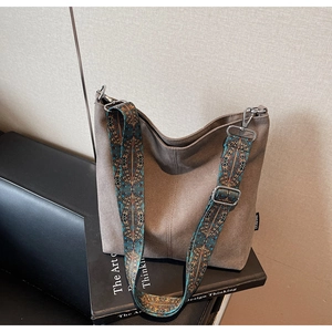 Détail d'un sac seau en toile vintage avec une bandoulière tissée aux motifs ethniques