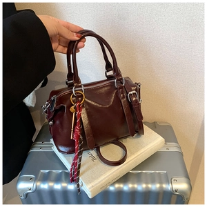 Détail du sac Boston bordeaux en cuir ciré avec des pendentifs en métal et en corde