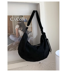 Detail of a large black crescent crossbody bag with a wide strap and a small coin pouch