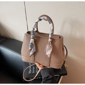 Detailed texture of brown pebble leather handbag with patterned silk scarf on handle