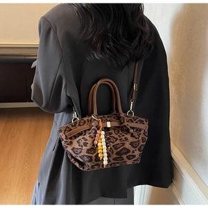 Detail of vintage leopard print crossbody bag featuring brown leather straps and beaded charm