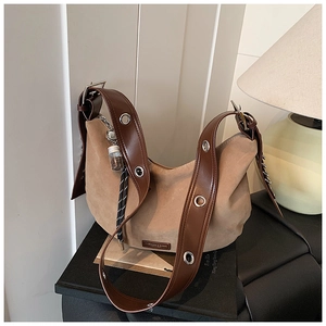 Détail du sac hobo en daim kaki avec œillets argentés et pendentif décoratif créatif