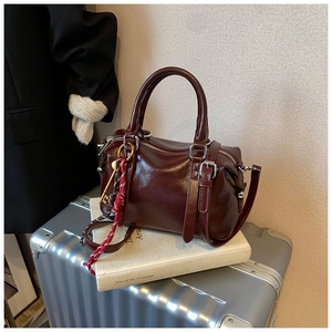 Détail du sac Boston en cuir ciré bordeaux avec ferrures argentées et pendentif