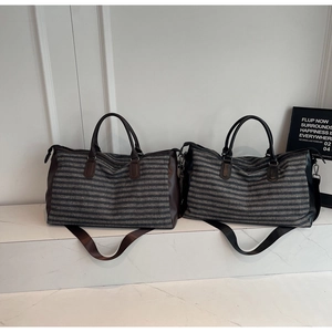 Detail of travel duffel bag showing stripe pattern, dual leather handles and shoulder strap