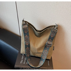 Détail d'un sac en toile vert olive avec bandoulière large aux motifs ethniques vintage