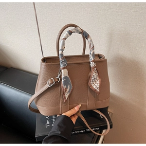 Litchi pattern leather bucket bag with printed silk scarf and adjustable strap on books