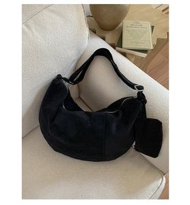 Macro detail of black suede hobo bag featuring silver zipper and detachable small coin pouch