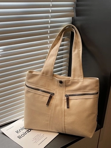 Minimalist beige canvas tote bag with dual front zipper pockets and top handles