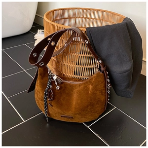 Détail du sac hobo en daim marron avec bandoulière à œillets et charms de perles en bois