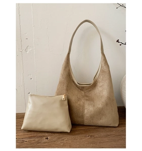 Detail view of khaki suede hobo bag and matching zippered pouch on a rustic wooden table