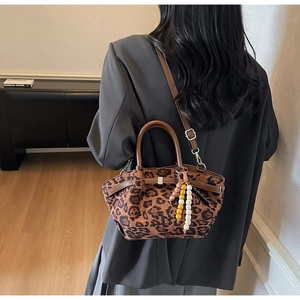 Detail of leopard print bucket bag with brown leather handle and colorful beaded charm
