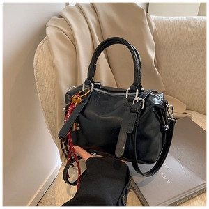 Détail du sac Boston en cuir ciré noir avec fermeture éclair argentée et breloque clé