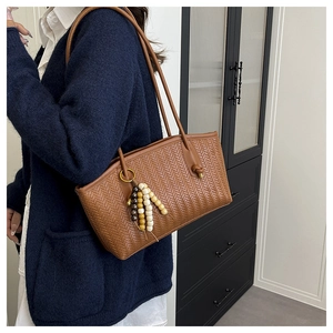 Close-up of brown woven tote bag with colorful wooden bead tassel and thin shoulder straps