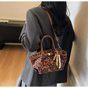 Detail of leopard print bucket bag with colorful beaded tassel and leather strap