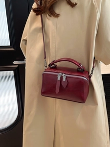 Elegante borsa a secchiello in pelle bordeaux indossata da una modella