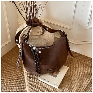 Détail du sac hobo en cuir mat marron foncé avec œillets argentés et breloque chaîne