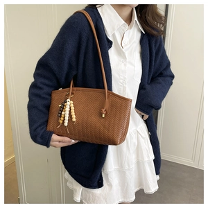 Close-up of brown woven tote bag with colorful wooden bead tassel charm detail