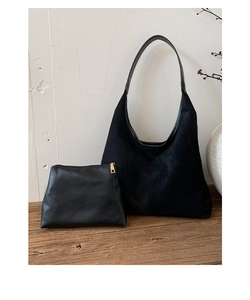 Detail of black suede hobo tote with matching leather pouch and gold hardware on wood