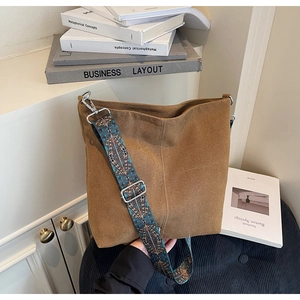 Détail d'un sac seau en toile marron avec une large bandoulière aux motifs ethniques