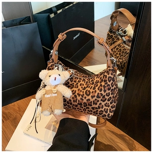 Detailed close-up of leopard print handbag with leather handle and fashion bear charm