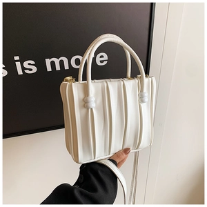 Detail of white pleated bucket bag with gold hardware and curved handles on black coat
