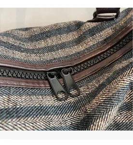 Close-up of herringbone fabric sports bag with smooth dual zippers and leather trim