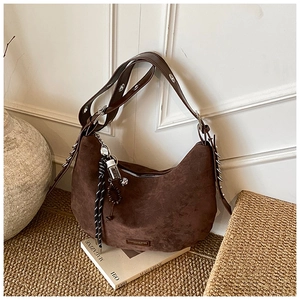 Détail d'un sac hobo marron rétro en suédine avec bandoulière à œillets métalliques