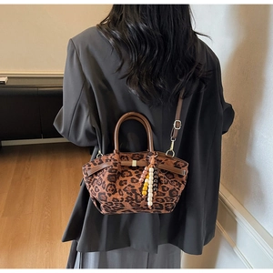 Close-up of leopard print bucket bag with brown leather handles and beaded charm