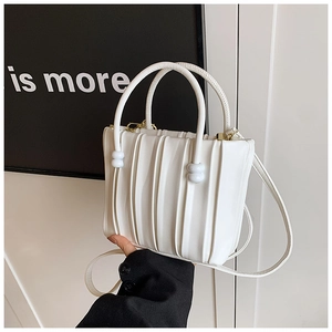 Detail of white pleated leather bucket bag with circular handles and adjustable strap