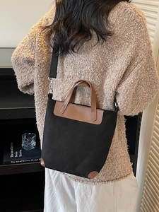 Black canvas hobo bag with brown leather trim and wide strap shown in a lifestyle setting
