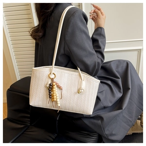 Close-up of white tote bag with herringbone texture and colorful wooden bead charm