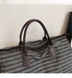 Detail view of durable herringbone fabric travel bag with brown leather handles and double zipper