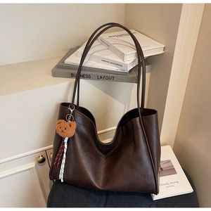 Detail of dark brown tote bag with natural texture and a cute teddy bear pendant