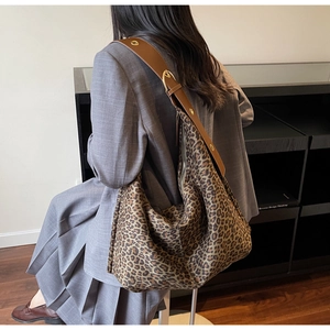 Détail du sac hobo léopard avec large bandoulière en cuir marron et boucles dorées
