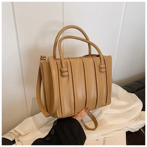 Close-up of pleated brown bucket bag with cylindrical handles and round knot details