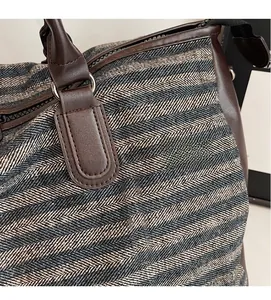 Close-up of herringbone tweed fabric texture and brown leather handle on gym bag