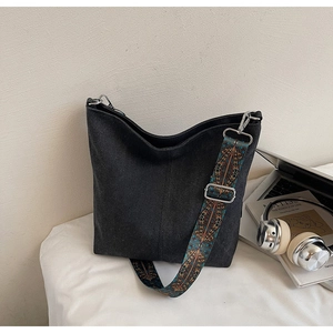 Détail du sac seau en daim noir avec large bandoulière brodée ethnique et finitions argentées