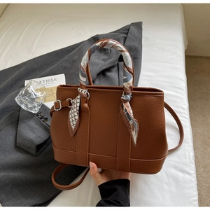 Detailed view of brown lychee grain leather bucket bag with silk scarf wrapped handle