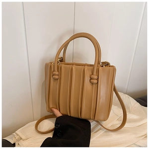 Detailed view of the camel pleated bucket bag showing vertical folds and knotted handles