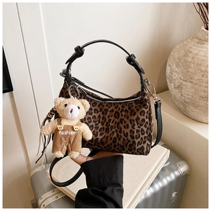 Close-up of leopard print handbag with black handle and a cute plush bear charm accessory