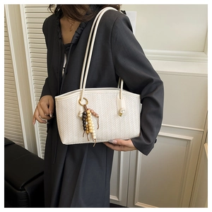 Detail of white woven tote bag featuring artisan wooden bead tassel and slim shoulder straps