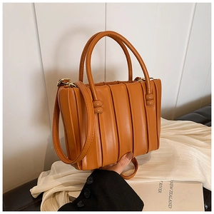 Detail of caramel pleated bucket bag showing vertical folds and matte faux leather texture