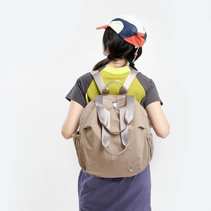 Detail view of khaki nylon backpack featuring pleated fabric and side elastic pocket